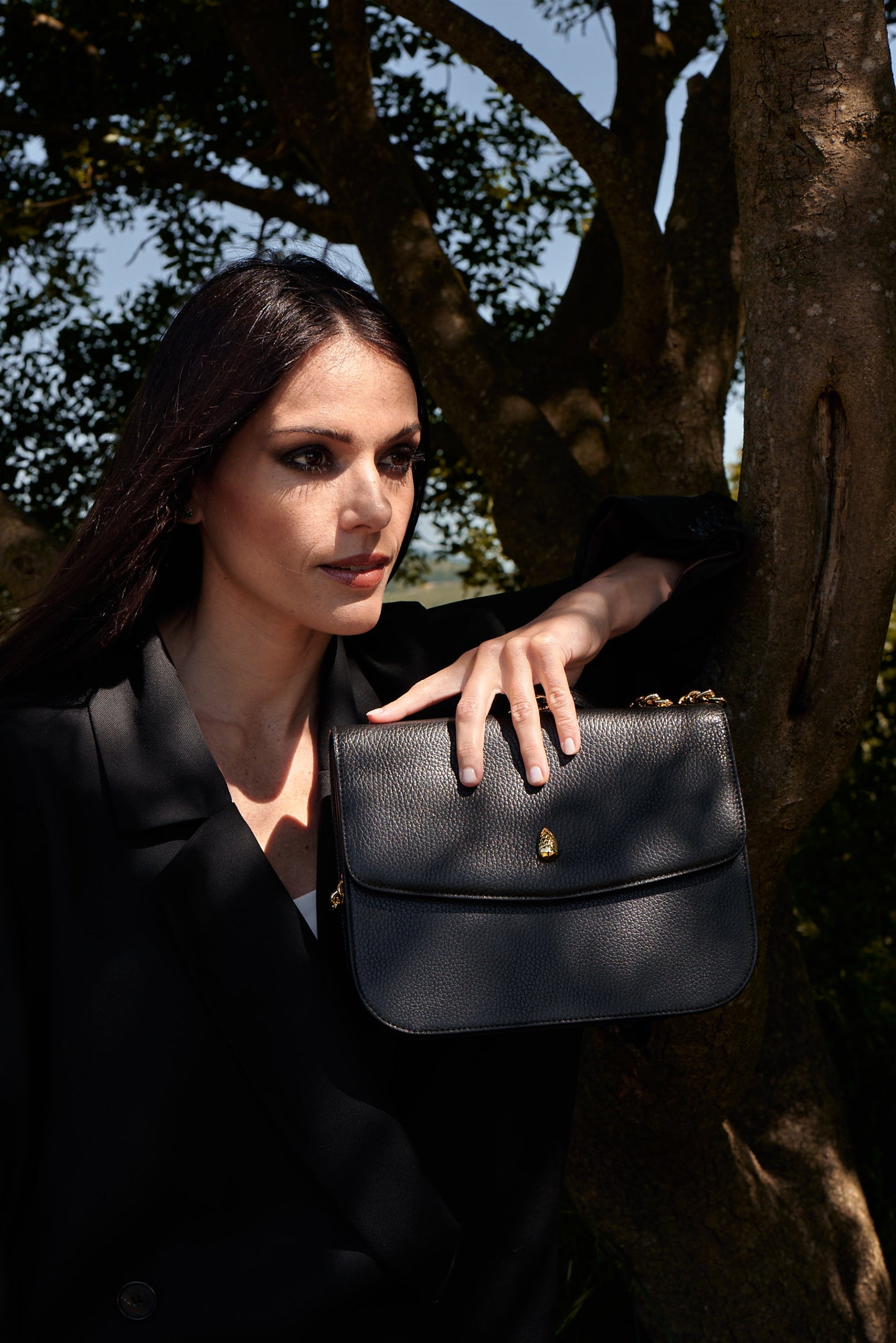 black leather shoulder bag worn with black blazer outdoor fashion shoot