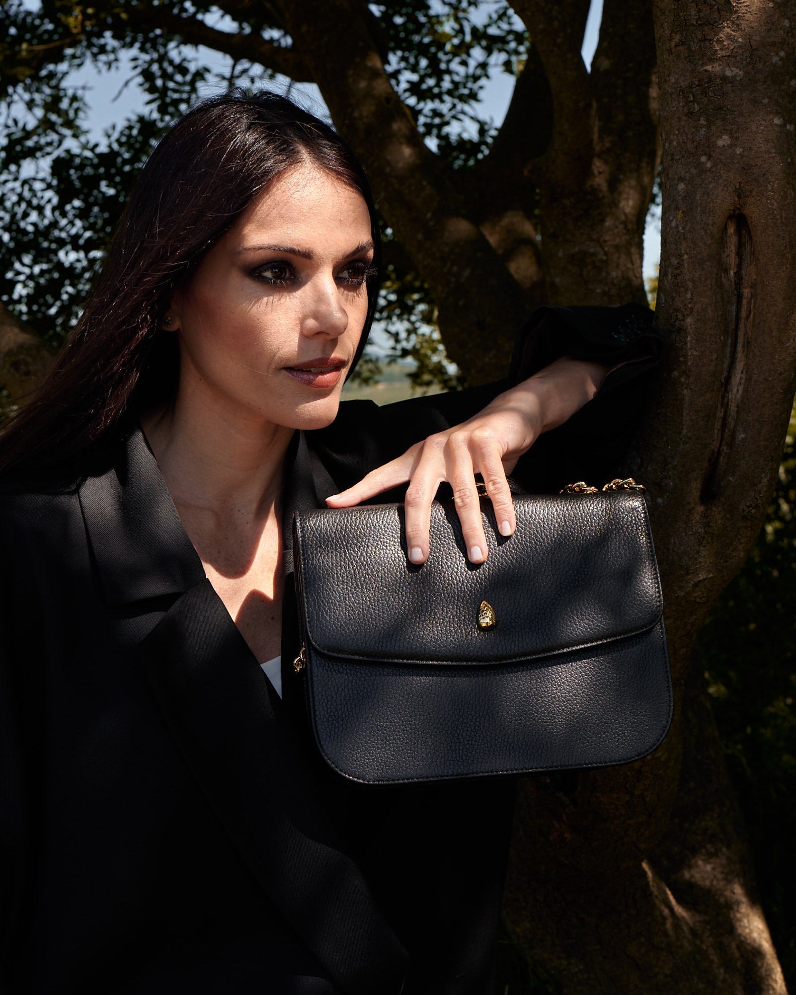 black leather shoulder bag worn with black blazer outdoor fashion shoot