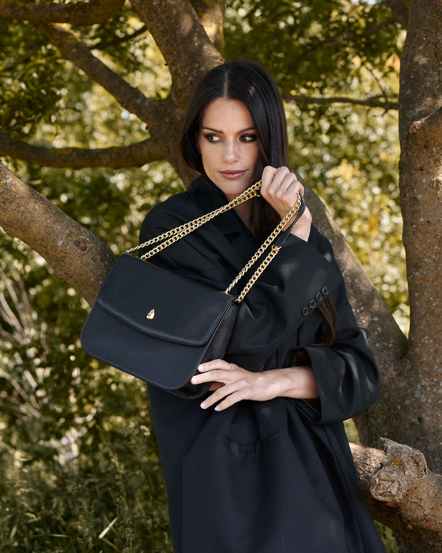 black leather shoulder bag held by gold chain strap close up detail