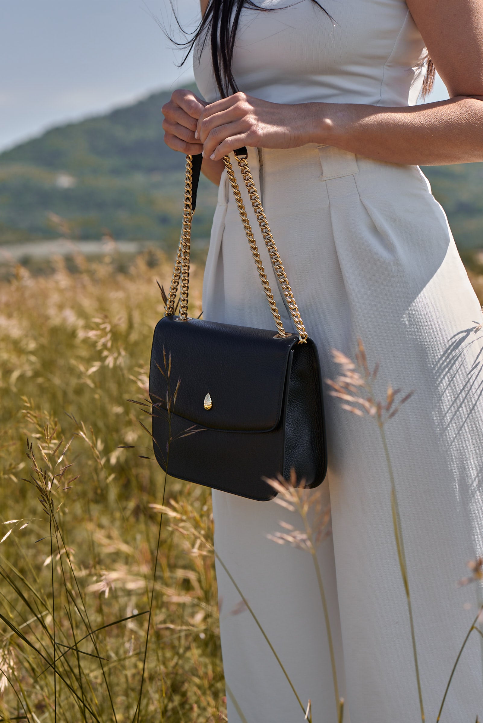 close up black leather shoulder bag textured leather gold clasp detail