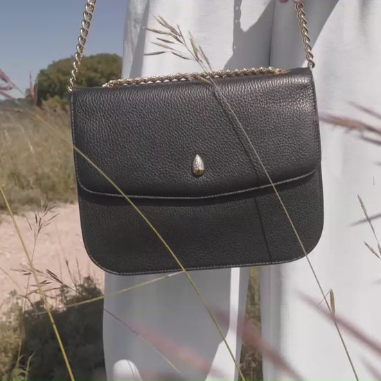 black leather shoulder bag gold chain worn by woman outdoor luxury style
