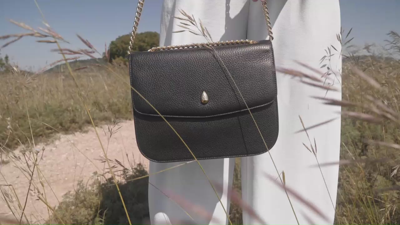 black leather shoulder bag gold chain worn by woman outdoor luxury style